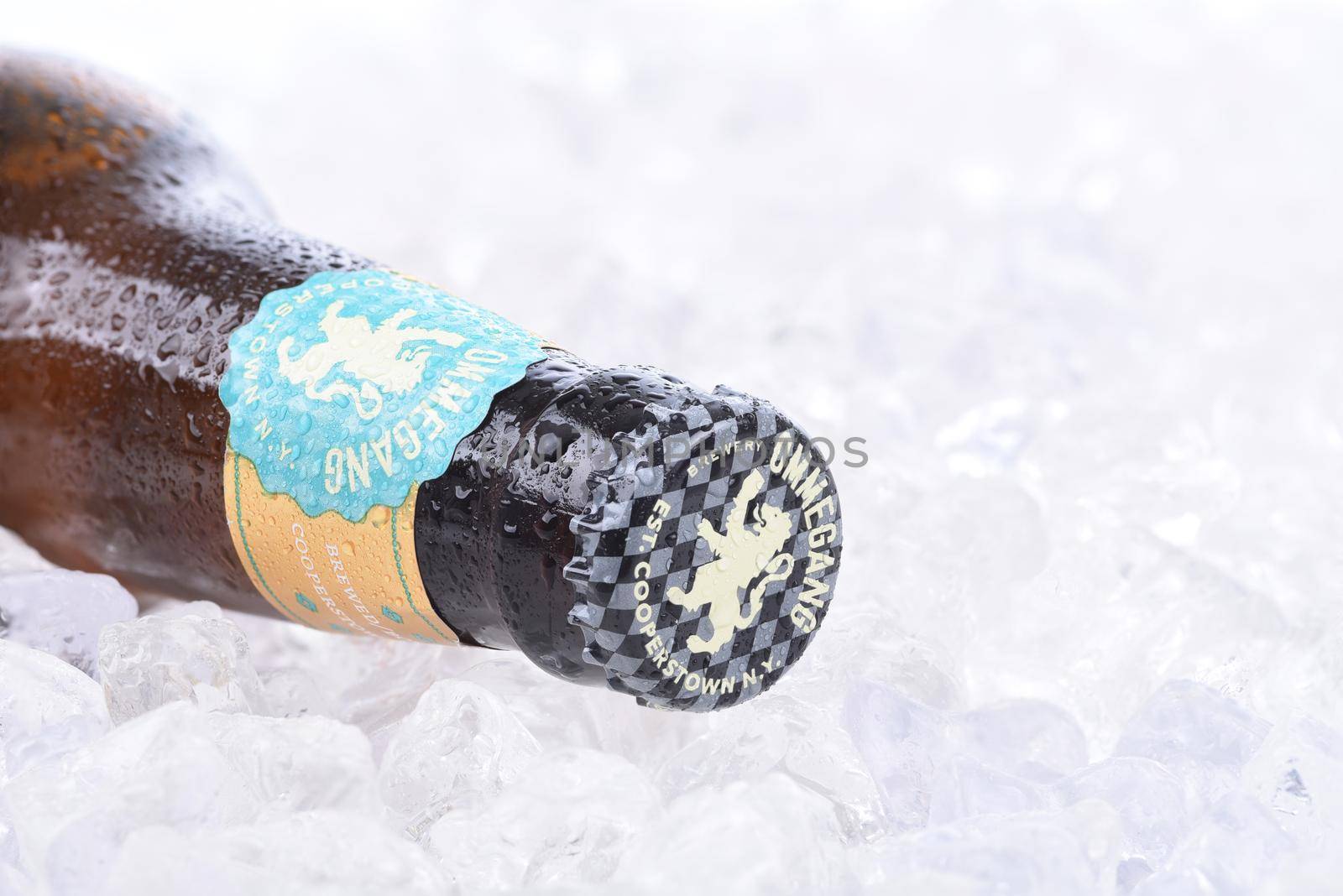 A bottle of Ommegang Wheat Ale in ice, cap closeup by sCukrov