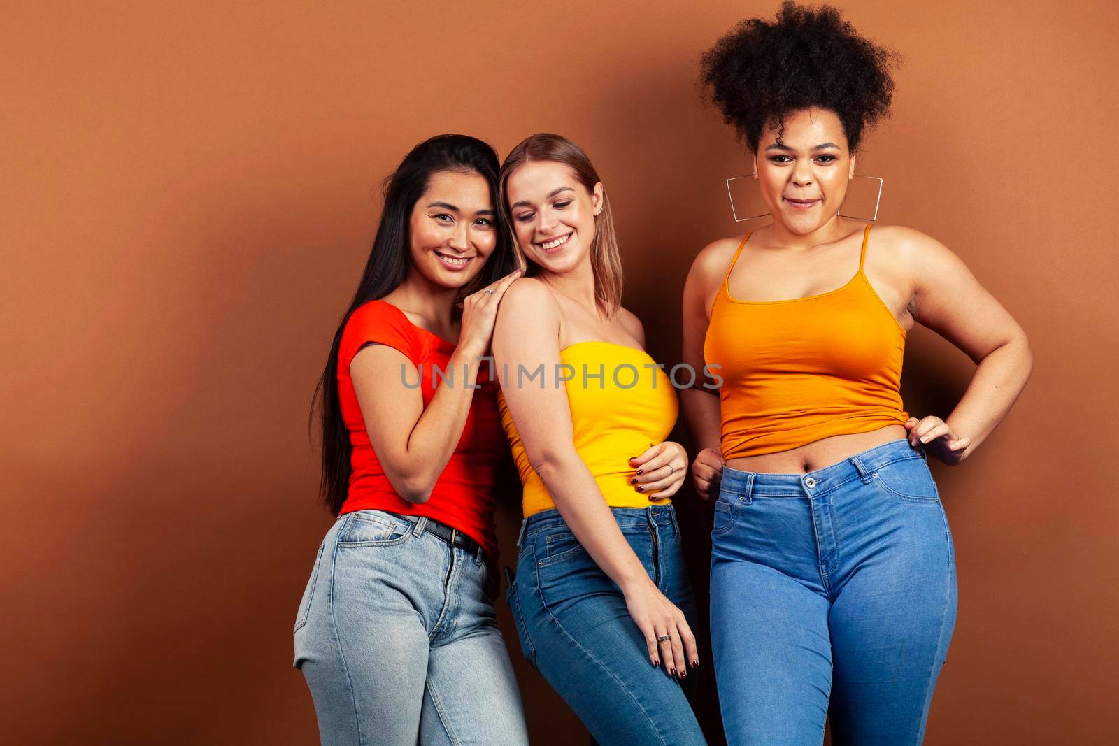 young pretty multiracial girls posing cheerful on brown background, lifestyle people concept by JordanJ
