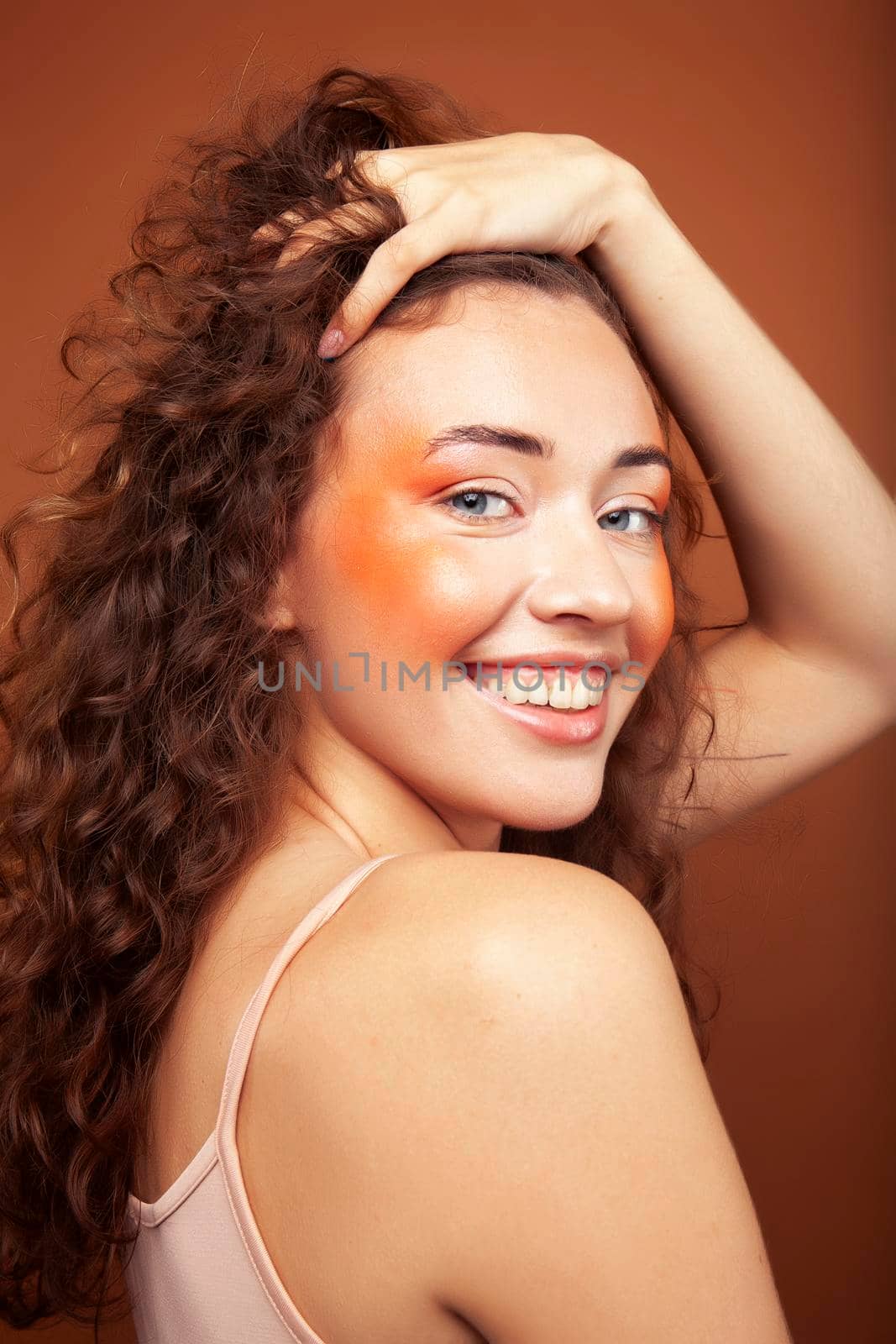 young pretty girl with blond curly hair posing cheerful on brown background, lifestyle people concept by JordanJ