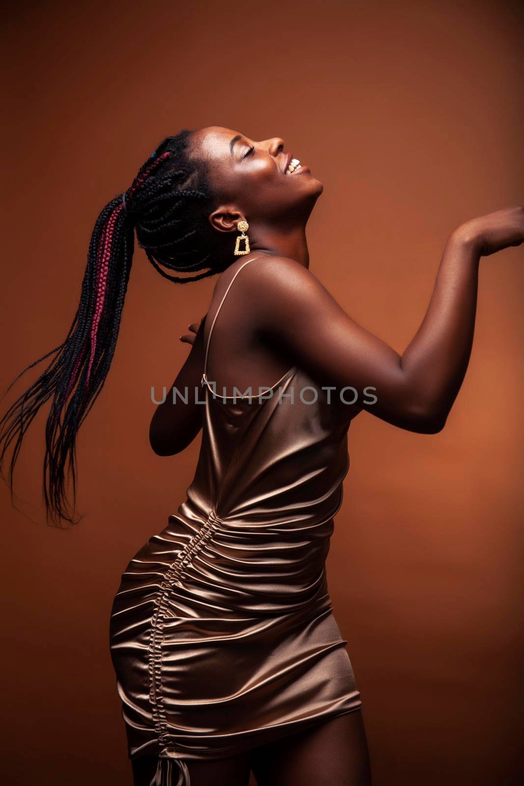 pretty young african american woman with curly hair posing cheerful gesturing on brown background, lifestyle people concept closeup