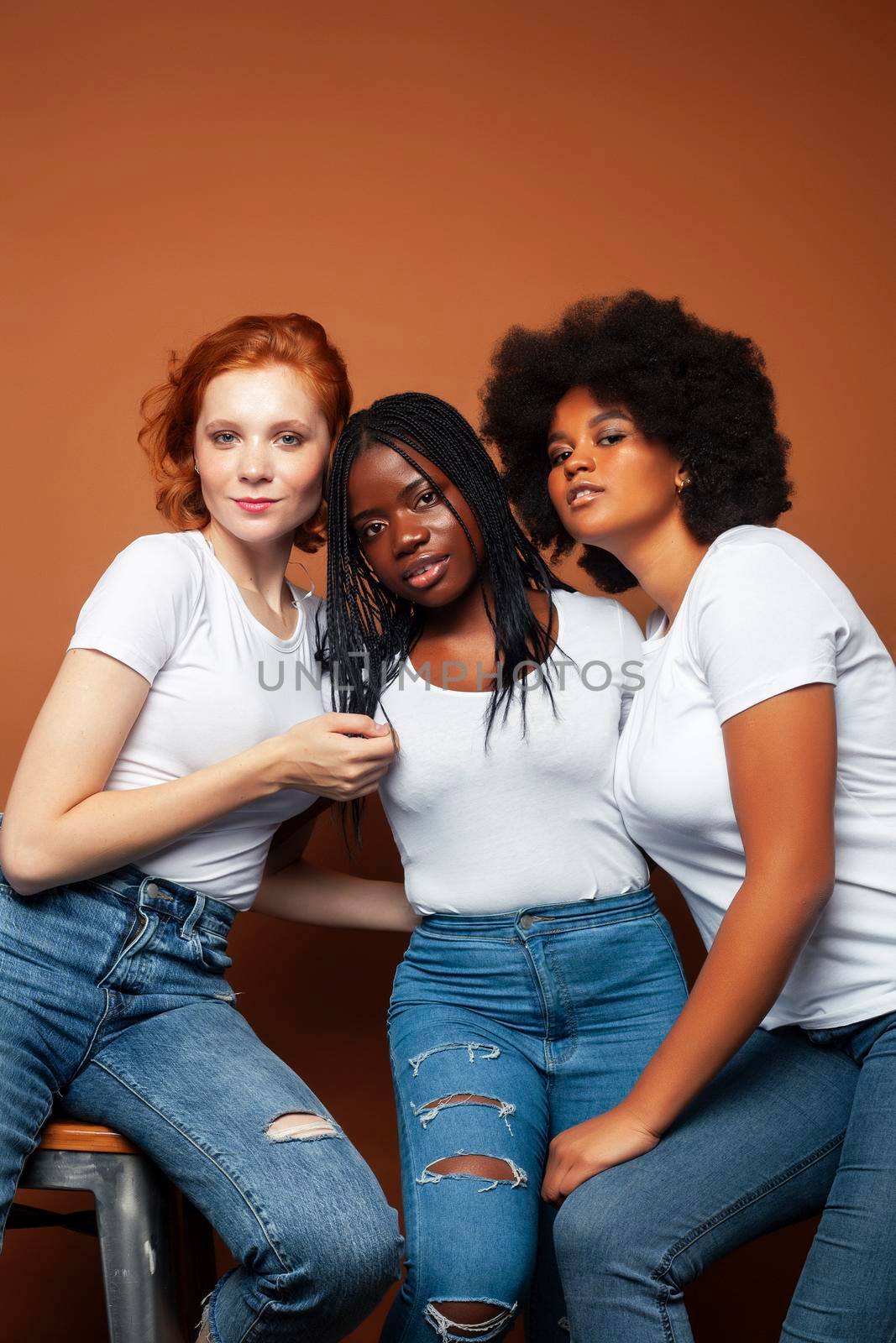 young pretty caucasian, afro, scandinavian woman posing cheerful together on brown background, lifestyle diverse nationality people concept by JordanJ