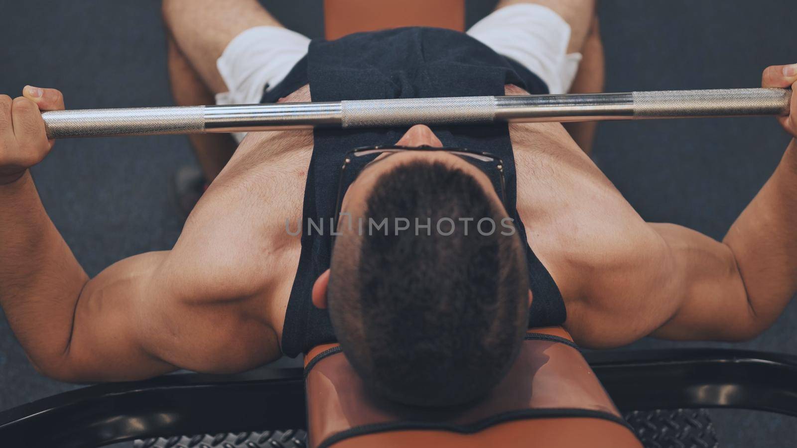 An Arab man shakes his chest with a barbell lying down. by DovidPro