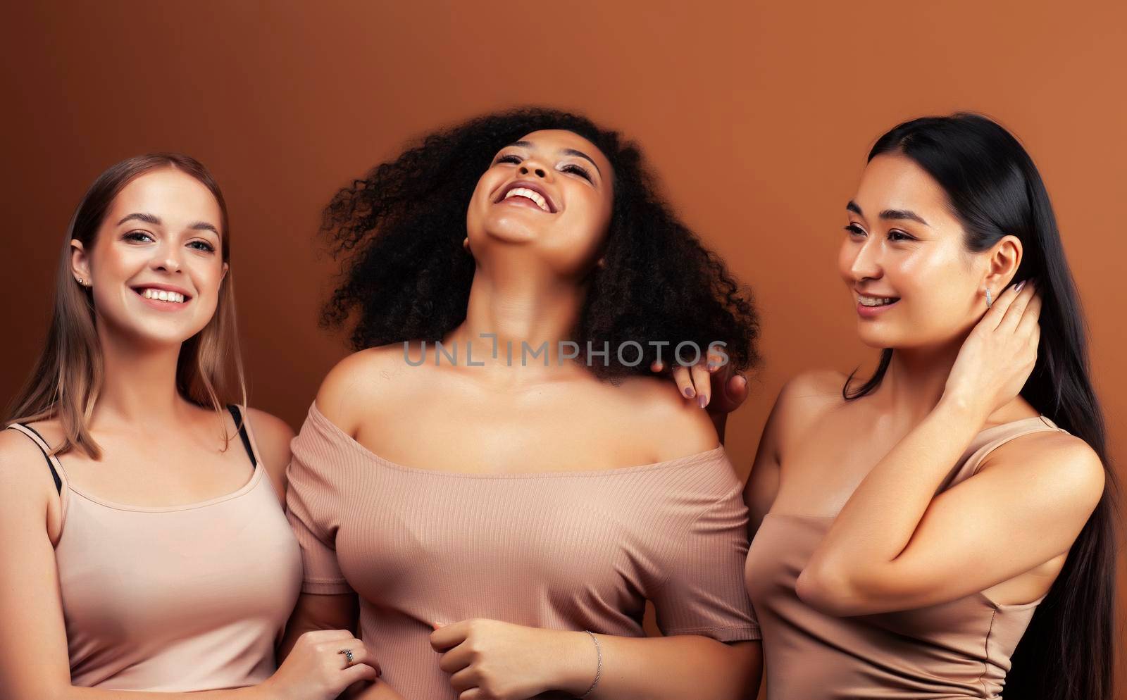 young pretty asian, caucasian, afro woman posing cheerful together on brown background, lifestyle diverse nationality people concept by JordanJ