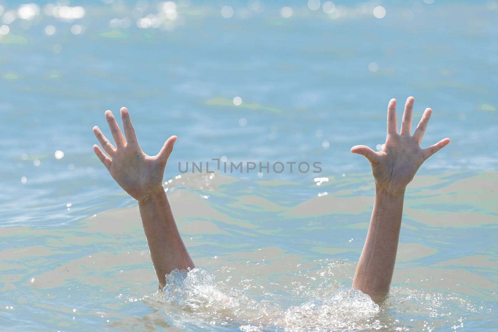 A hands from under the water of a drowning girl, help and urgent rescue of a person during a dangerous swimming, sos.