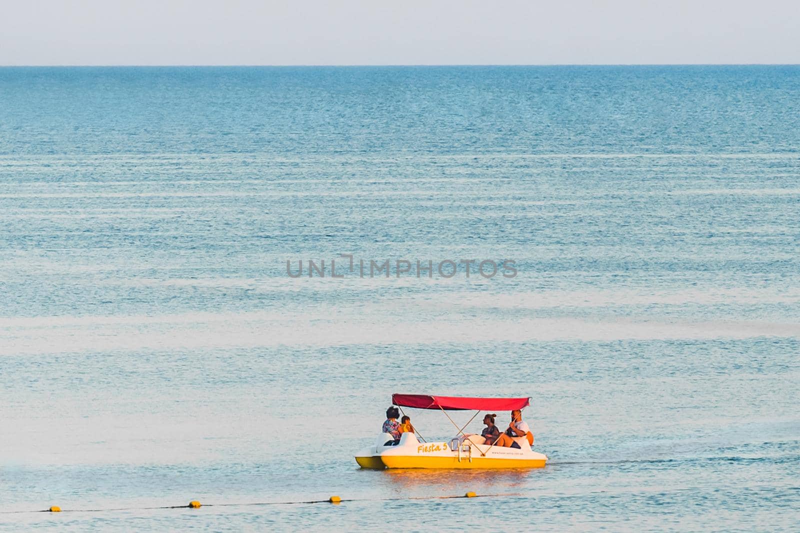 Ukraine, Iron Port - August 22, 2020: Tourists group swim on a pedal boat on the background of the sea near the shore.