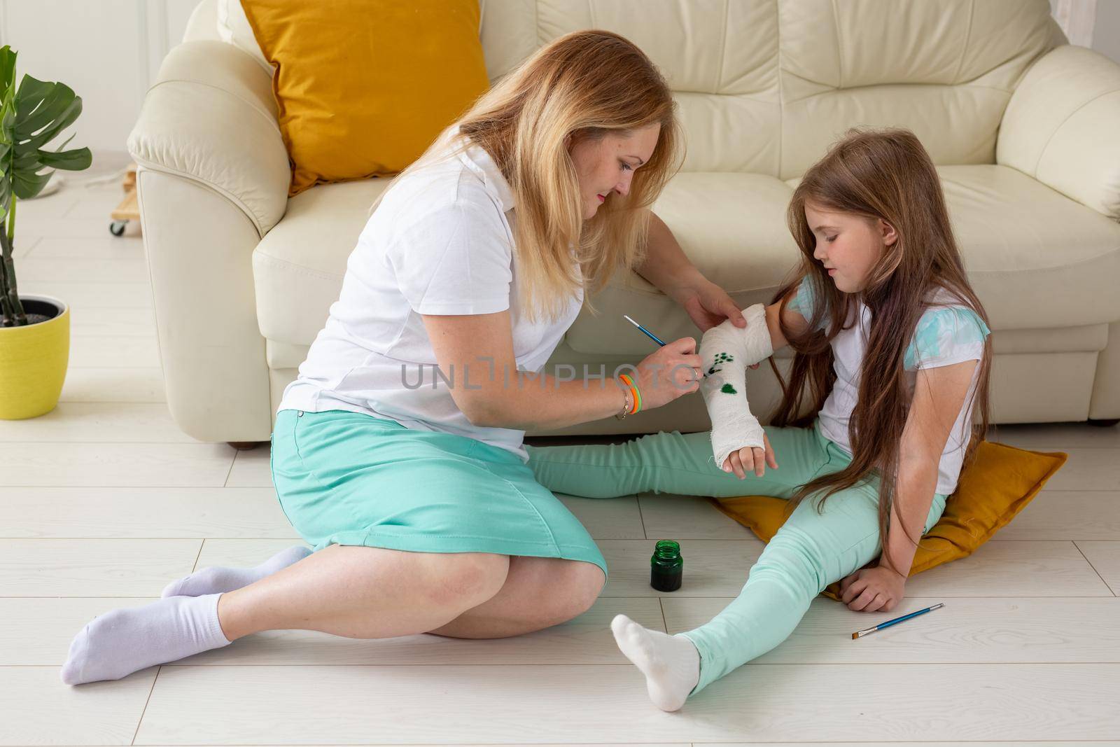 Mother and daughter drawing picture on bandage using paints. Play therapy concept. by Satura86