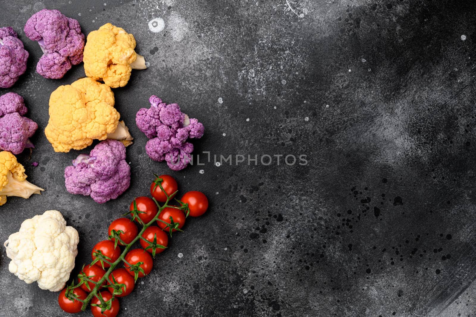 Purple yellow and white cauliflower set, on black dark stone table background, top view flat lay, with copy space for text