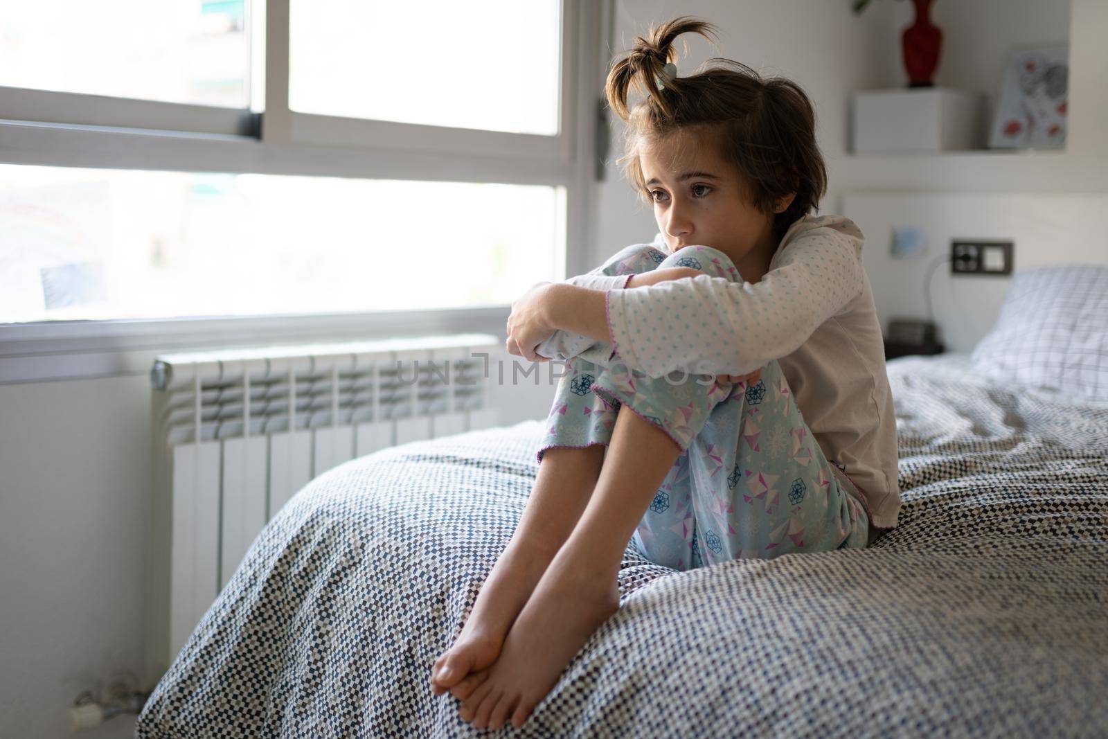 Nine-year-old girl sitting in bed bored by confinement by javiindy