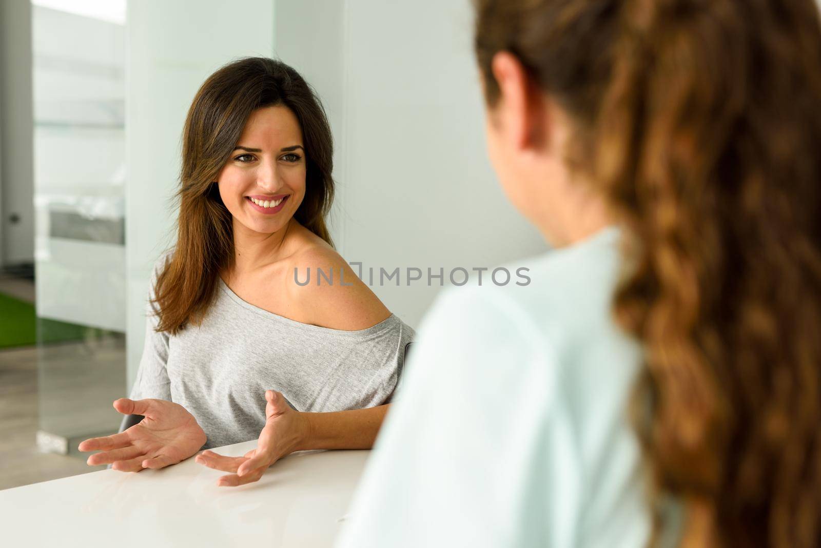 Female physiotherapist explaining diagnosis to her patient. Brunette woman having consultation with girl in medical office.