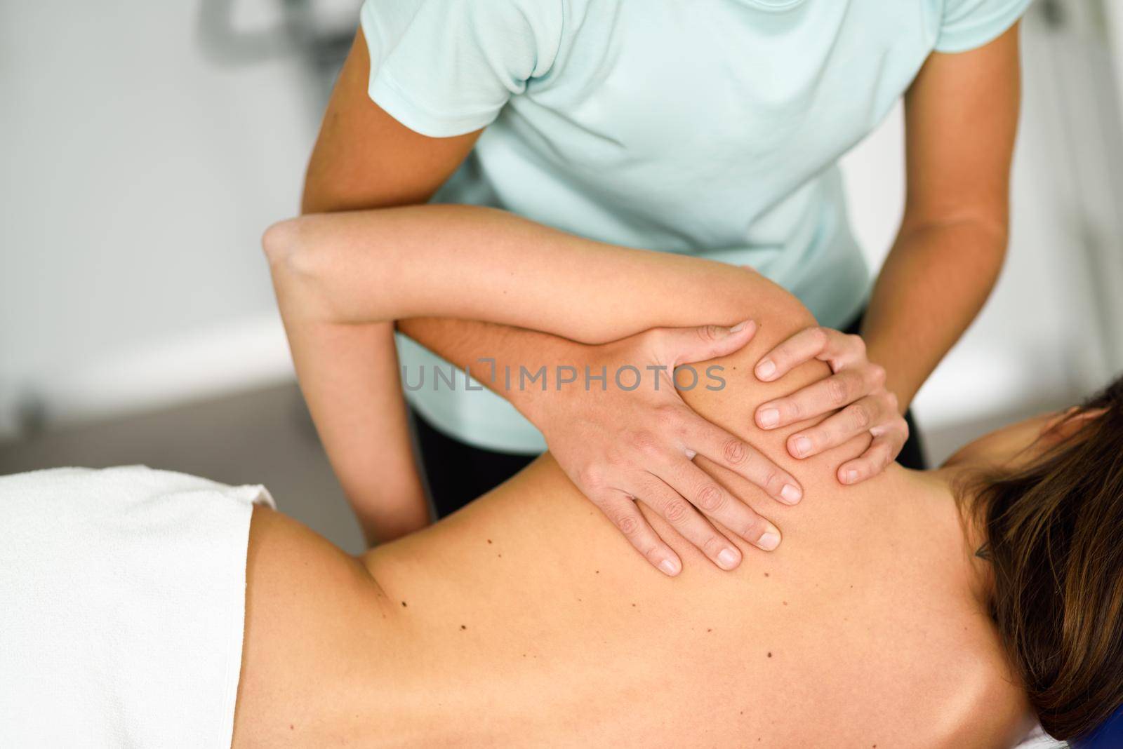 Professional female physiotherapist giving shoulder massage to a woman by javiindy