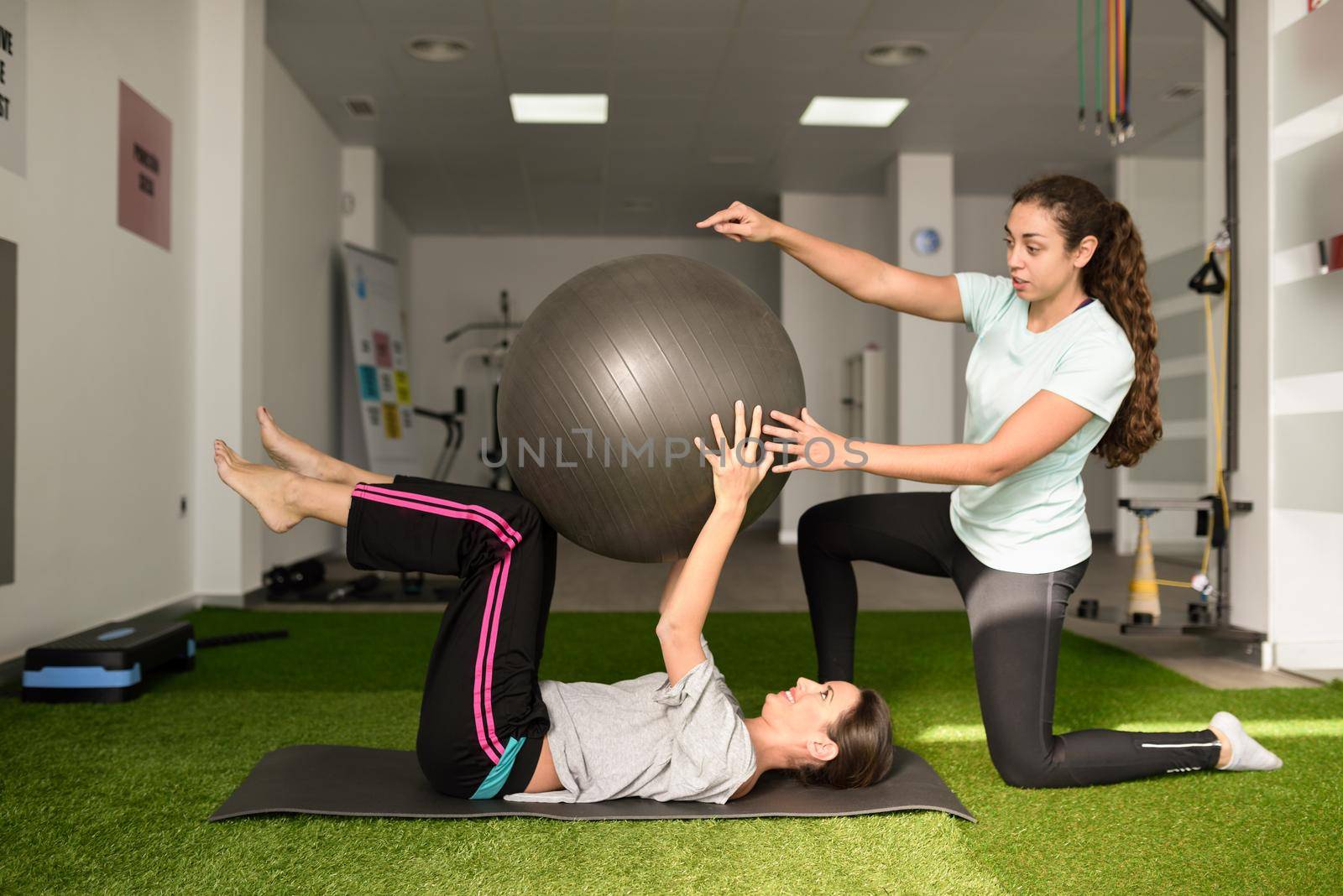 Physical therapist assisting young caucasian woman with exercise by javiindy