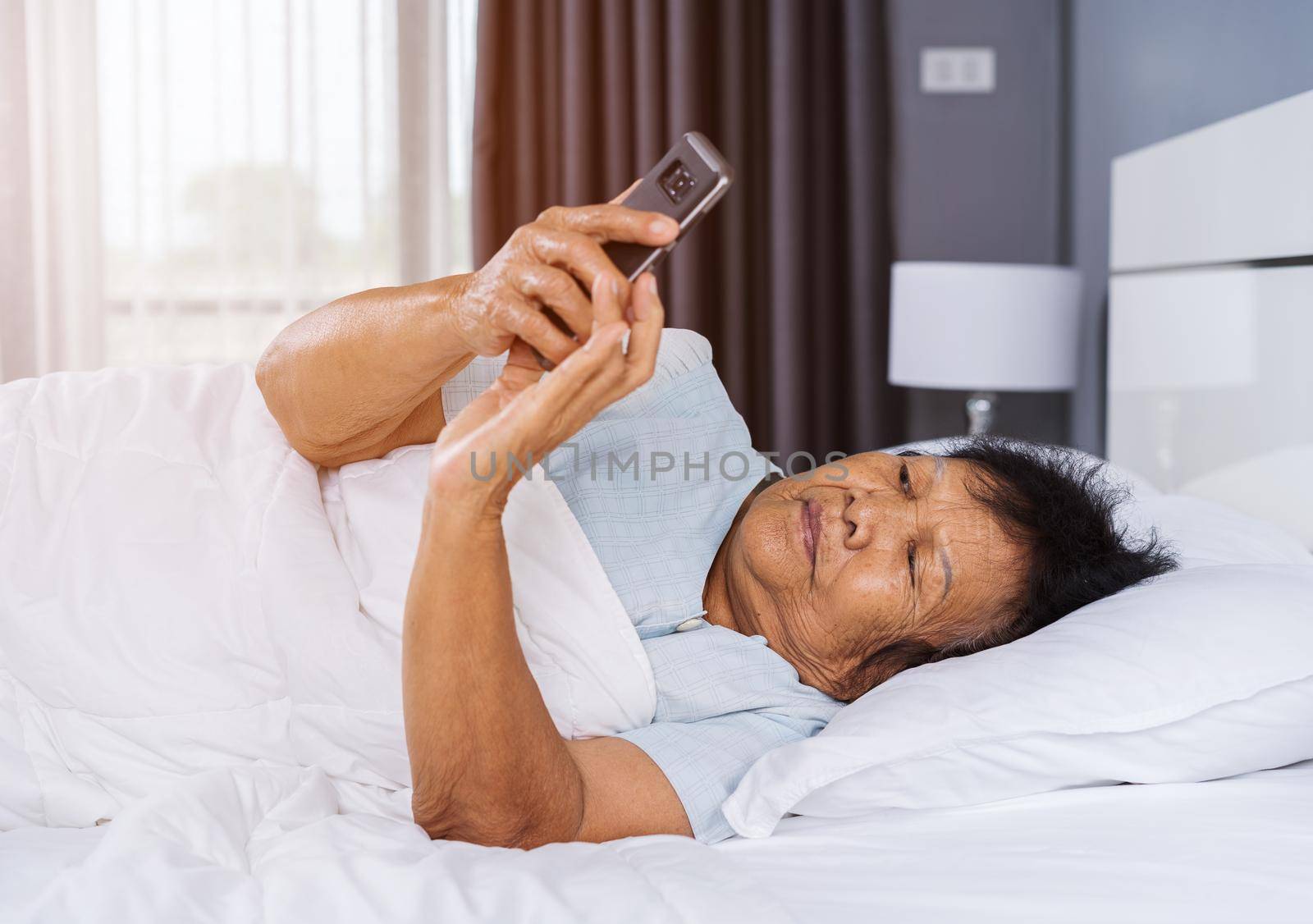 senior woman using mobile phone on a bed