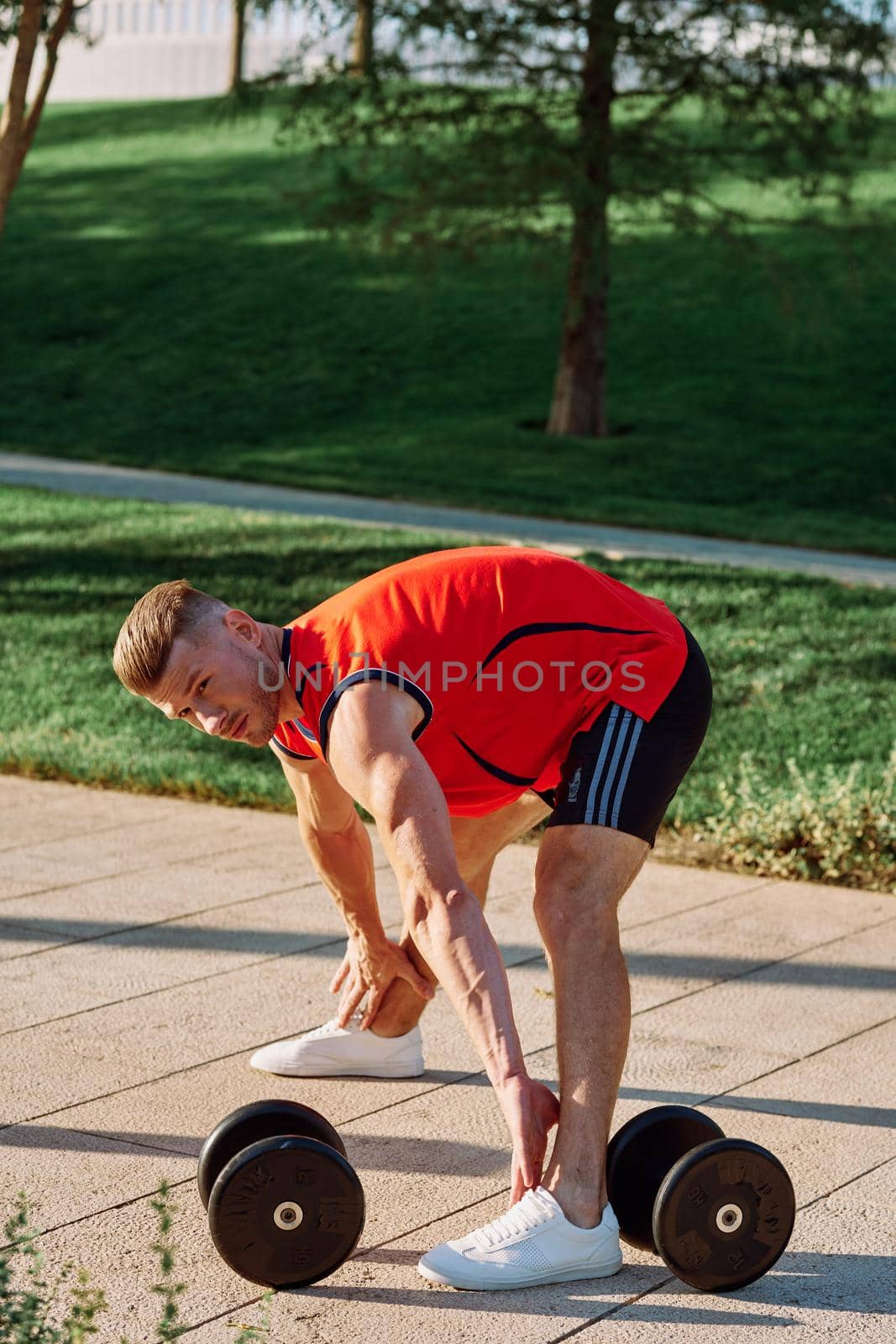 sporty man in the morning in the park with dumbbells exercise by Vichizh