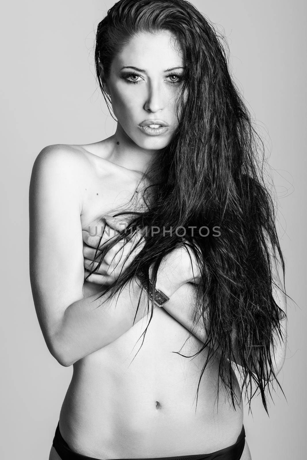 Half naked brunette woman wearing panties with very long curly hair on white background. Studio shot