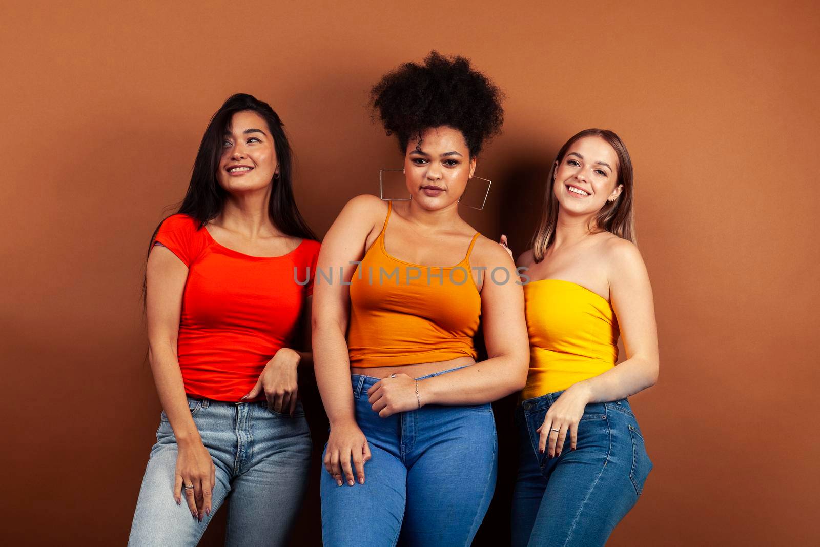 young pretty multiracial girls posing cheerful on brown background, lifestyle people concept by JordanJ