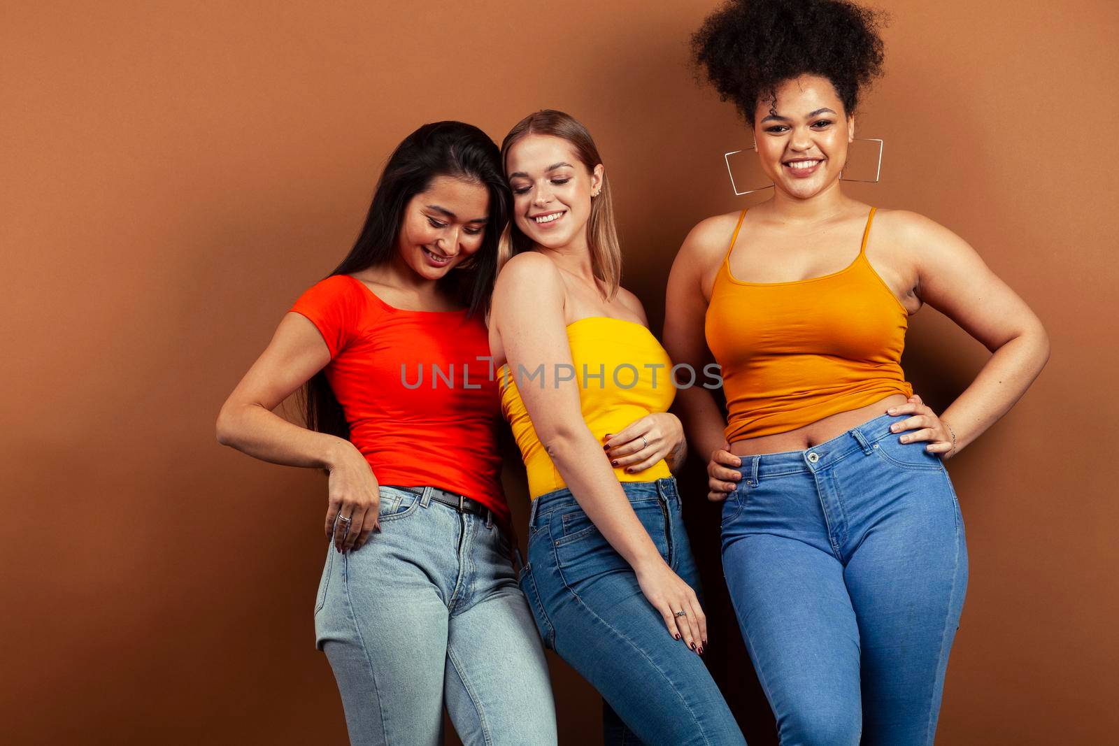 young pretty multiracial girls posing cheerful on brown background, lifestyle people concept by JordanJ