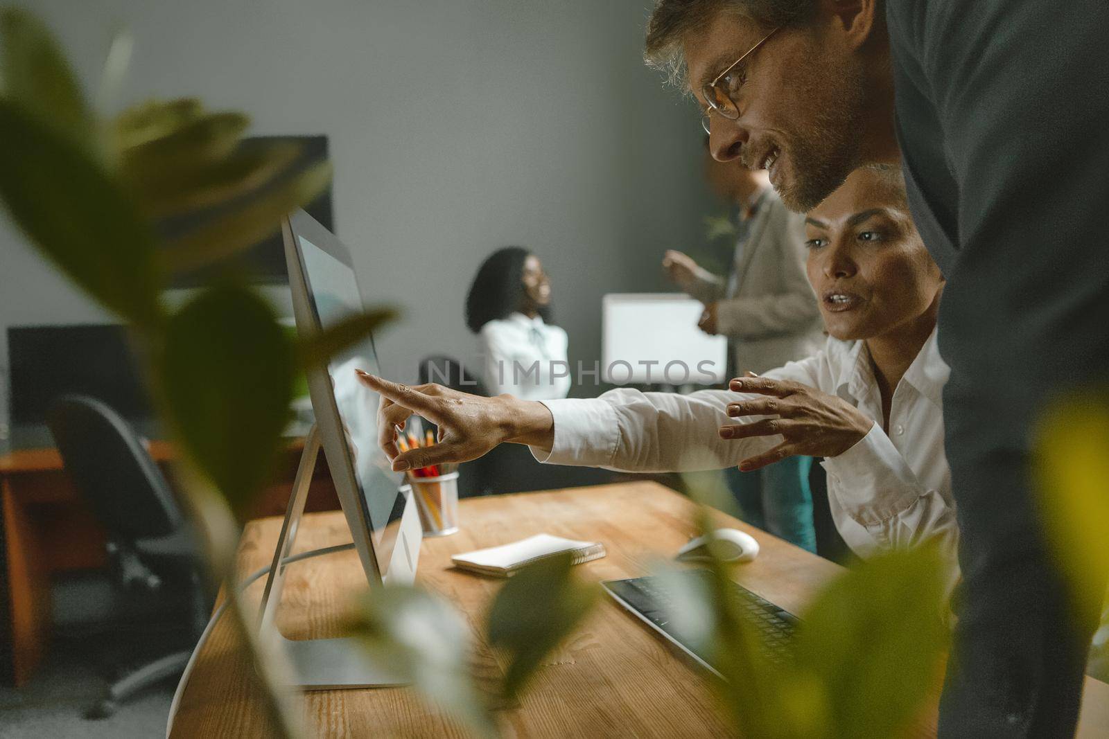 Coworking team with girl showing to her supervisor new settings. Employees work hard in the team to delivery the project. Teamwork concept by LipikStockMedia