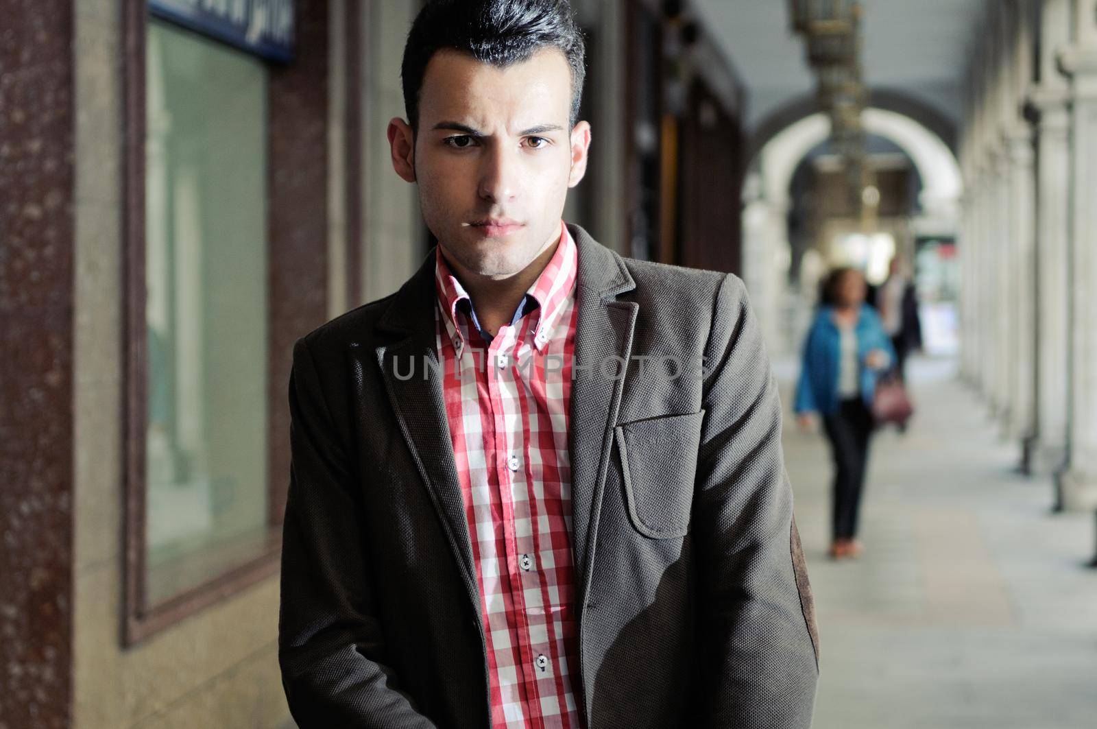 Portrait of a young handsome man, model of fashion, wearing jacket and shirt in urban background