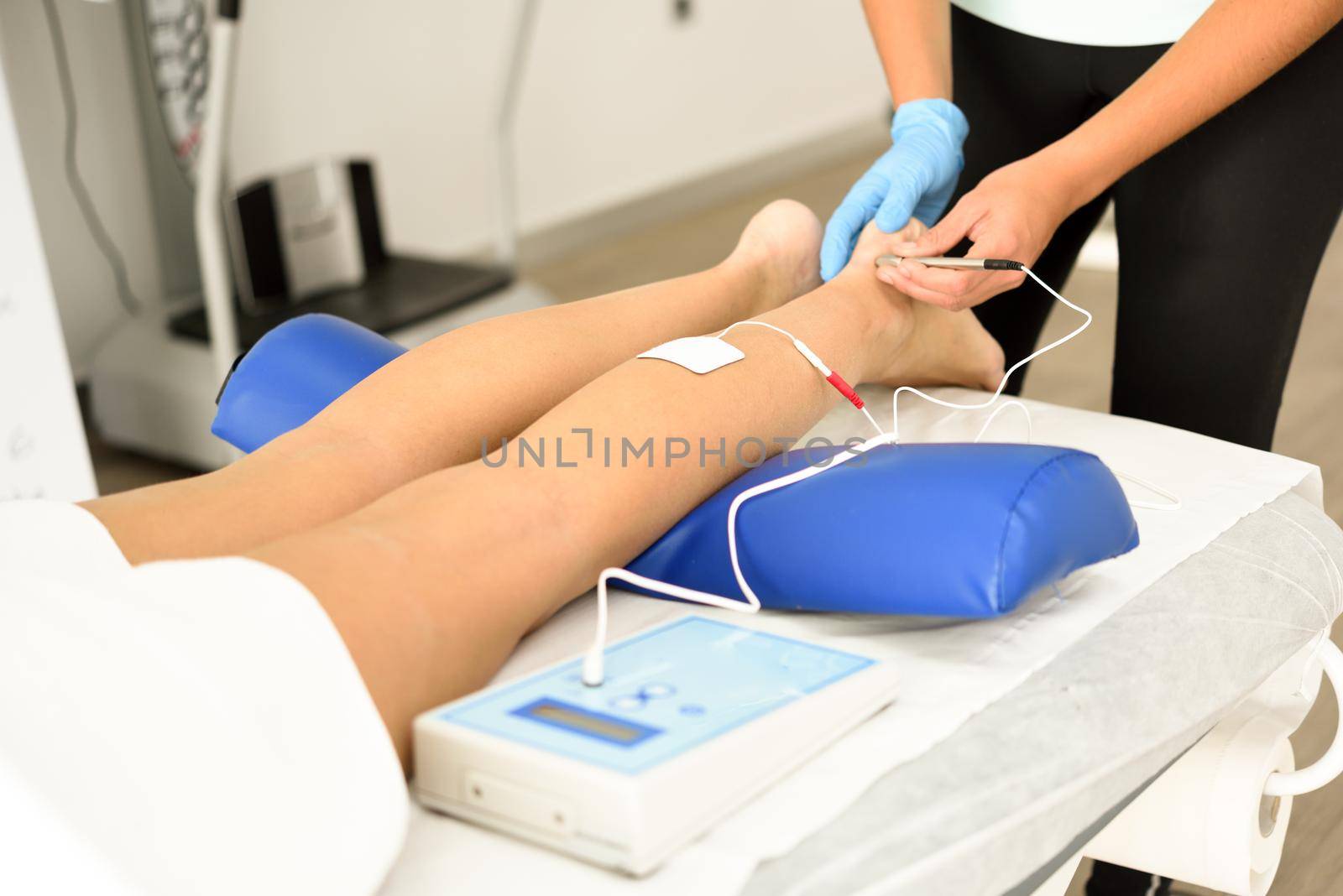 Electroacupuncture dry with needle connecting machine used by acupunturist on female patient for acupuncture guided by EPI Intratissue Percutaneous Electrolisis. Electro stimulation in physical therapy to ankle of a young woman in physiotherapy center.