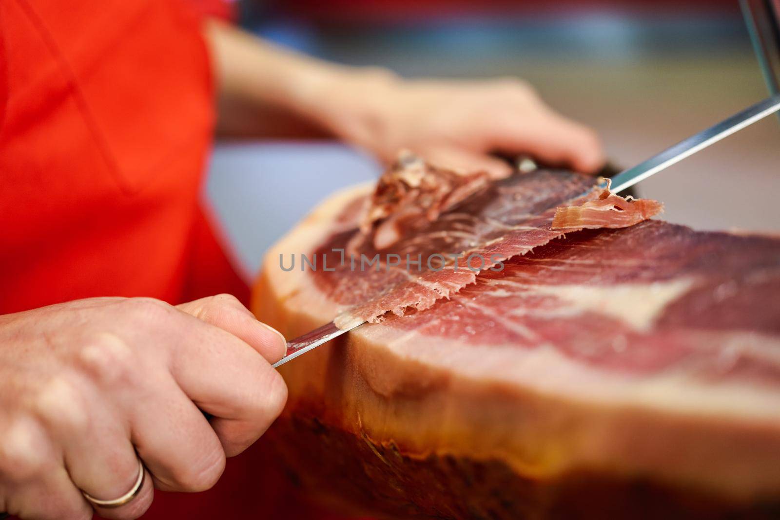 Close-up of professional cutter carving slices from a whole bone-in serrano ham