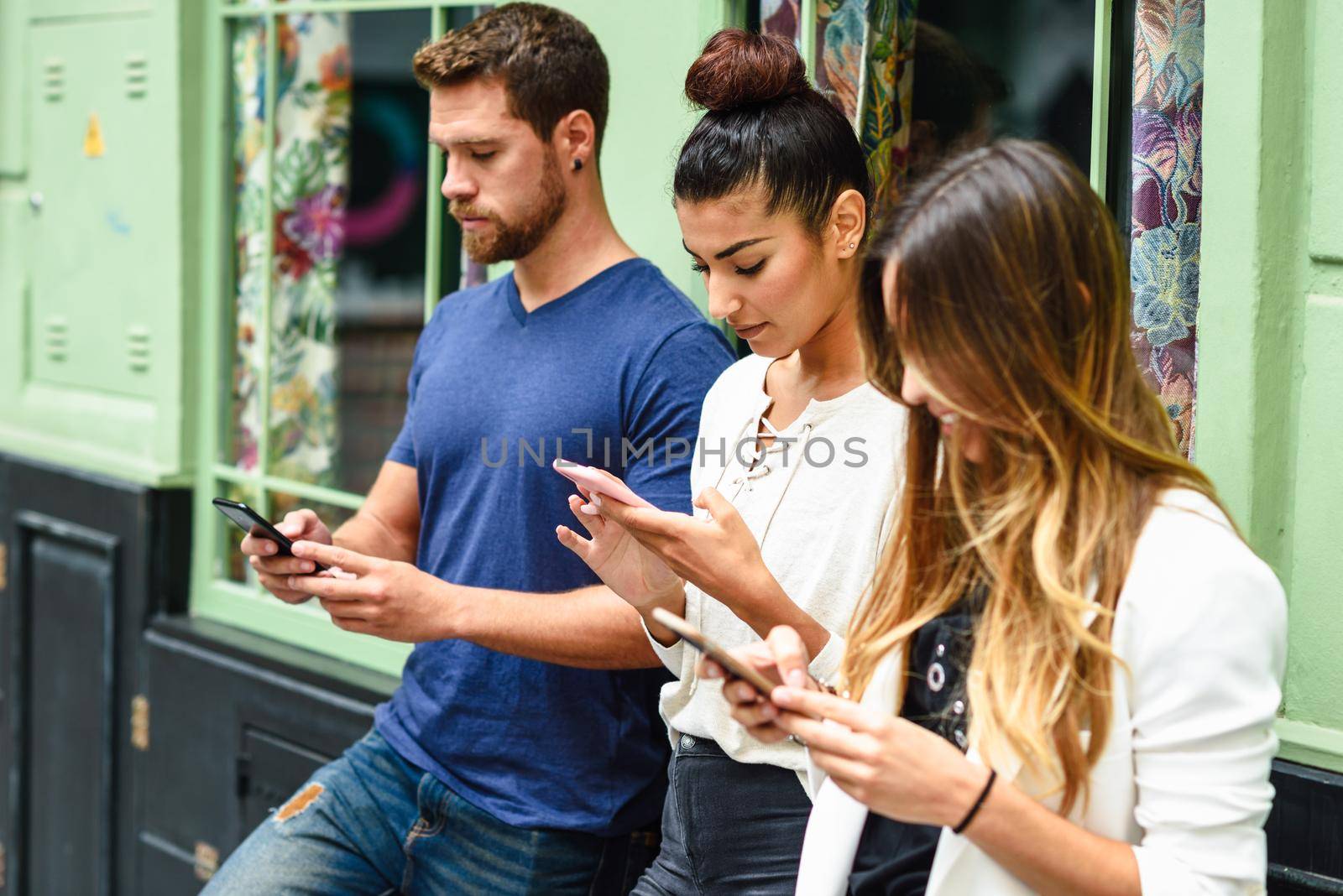 Multiracial group of people looking down at smart phone by javiindy