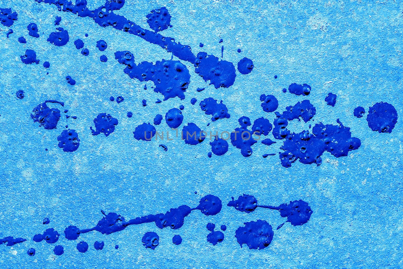 Blue paint splashes on concrete wall surface texture background.