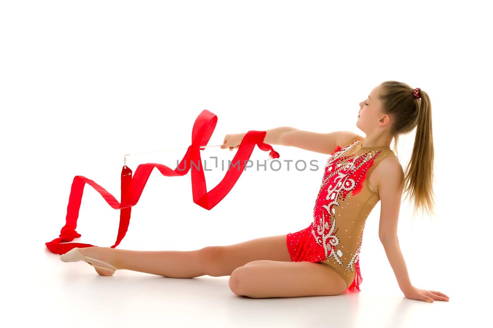 Little girl gymnast performs exercises with tape. The concept of sport, competition. Isolated on white background.