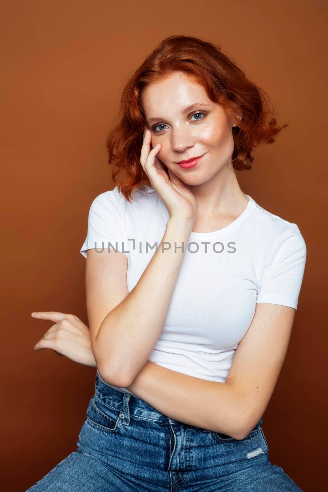 young pretty redhead girl posing cheerful on warm brown background, lifestyle people concept close up