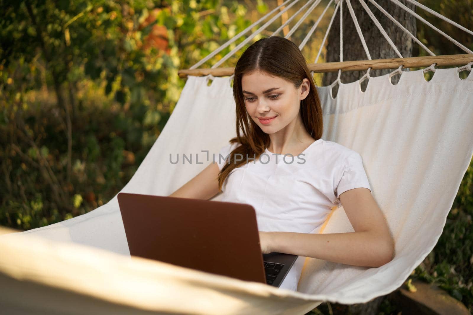 woman lies in a hammock with laptop on nature vacation travel. High quality photo