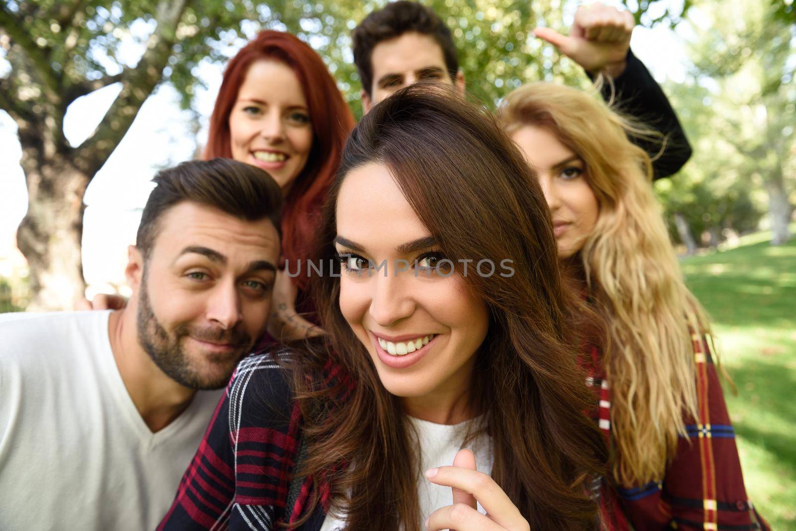 Group of young people together outdoors in urban background. Women and men sitting on stairs in the street wearing casual clothes.