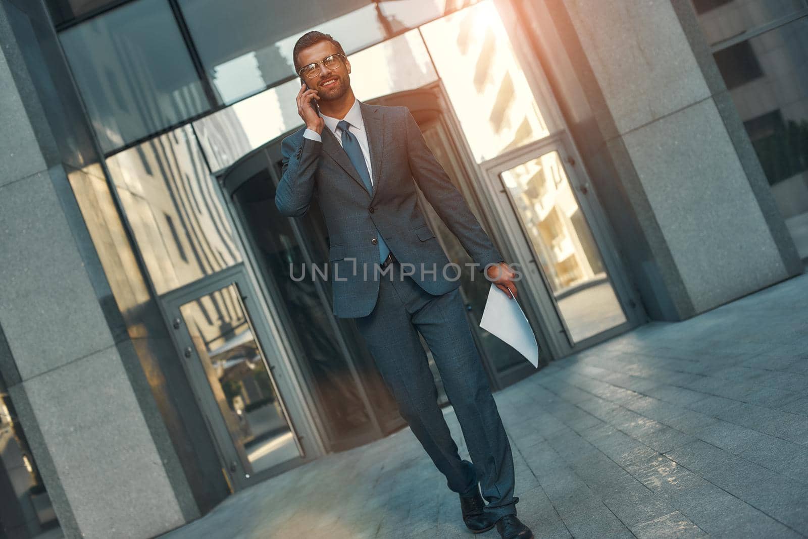 Happy to hear you Portrait of smiling bearded businessman in full suit talking by phone with client while walking outdoors. Business concept