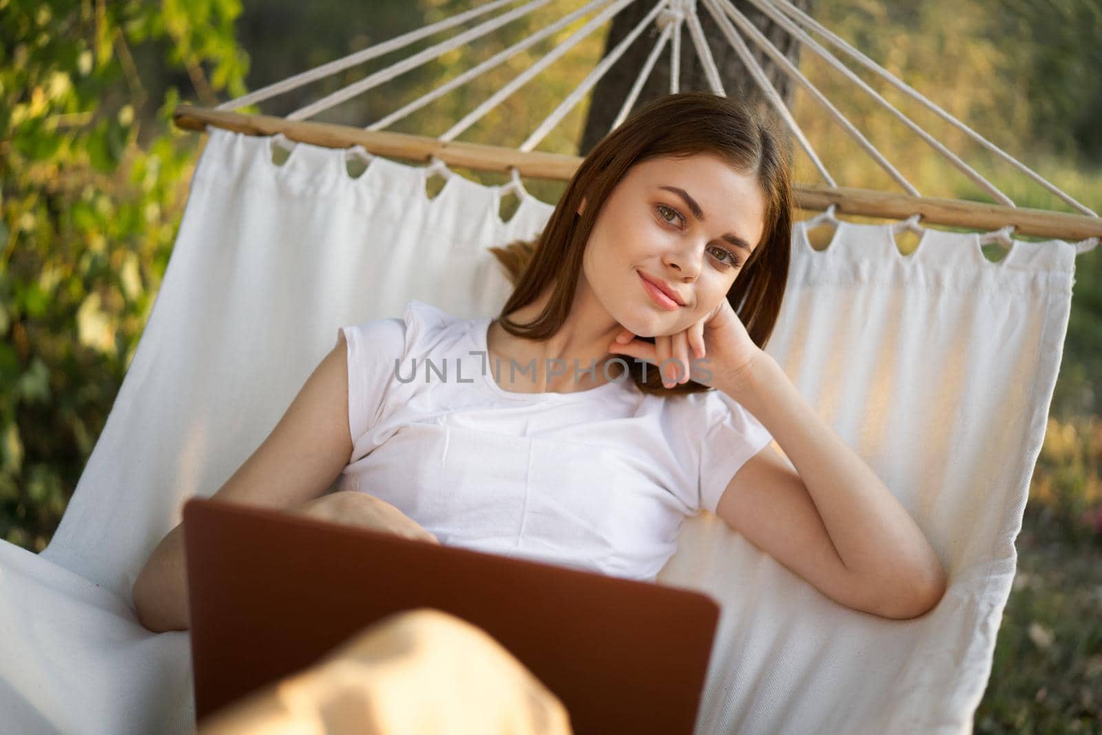 woman working in front of laptop in a hammock in nature. High quality photo