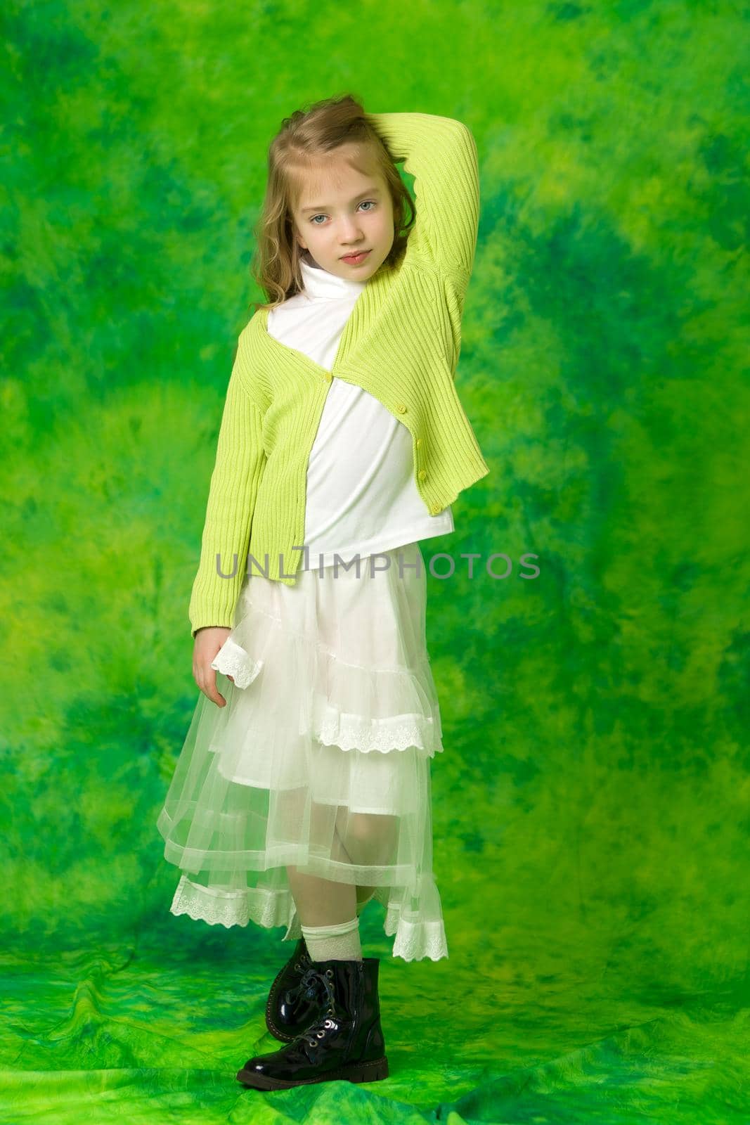 A charming little school girl corrects her long silky hair with her hands. The concept of style and fashion, happy people.