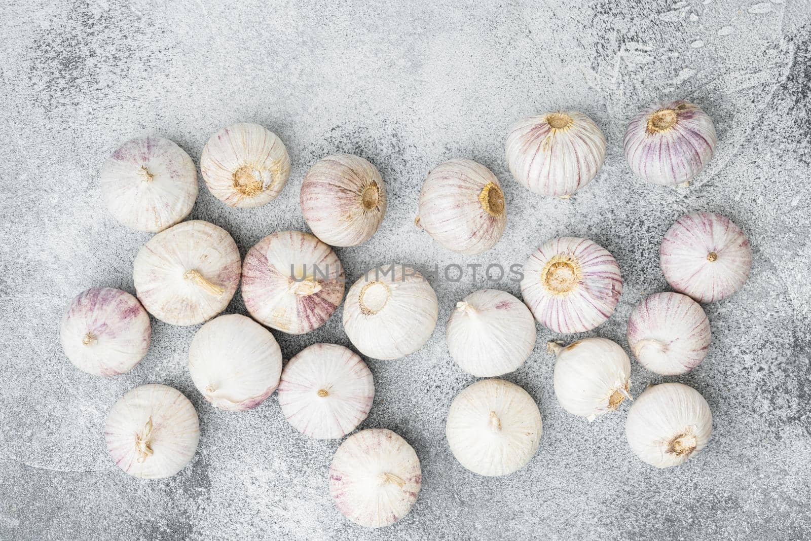Small fresh garlic set, on gray stone table background, top view flat lay
