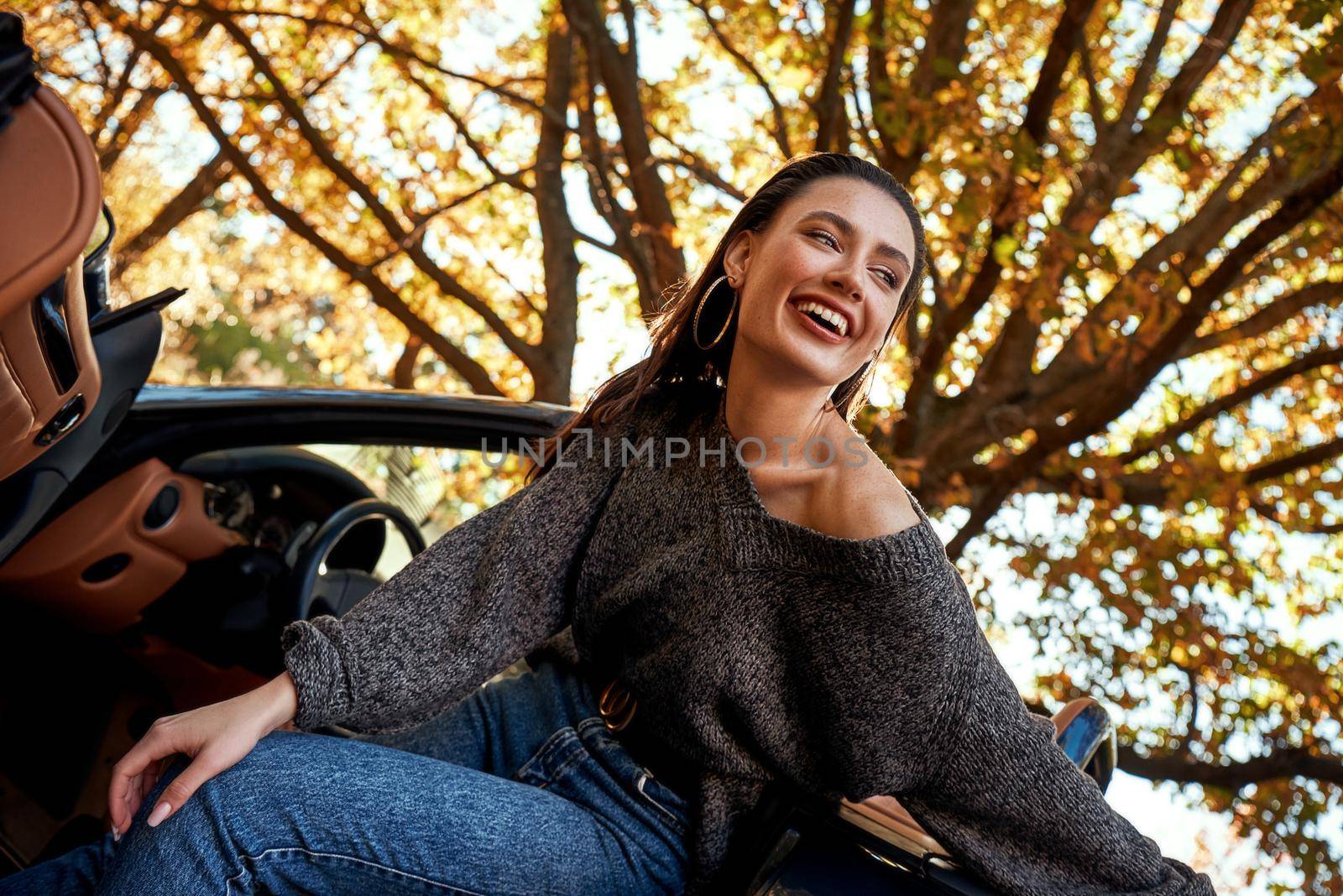 Sexy young woman in jeans smiling in a cabriolet by friendsstock