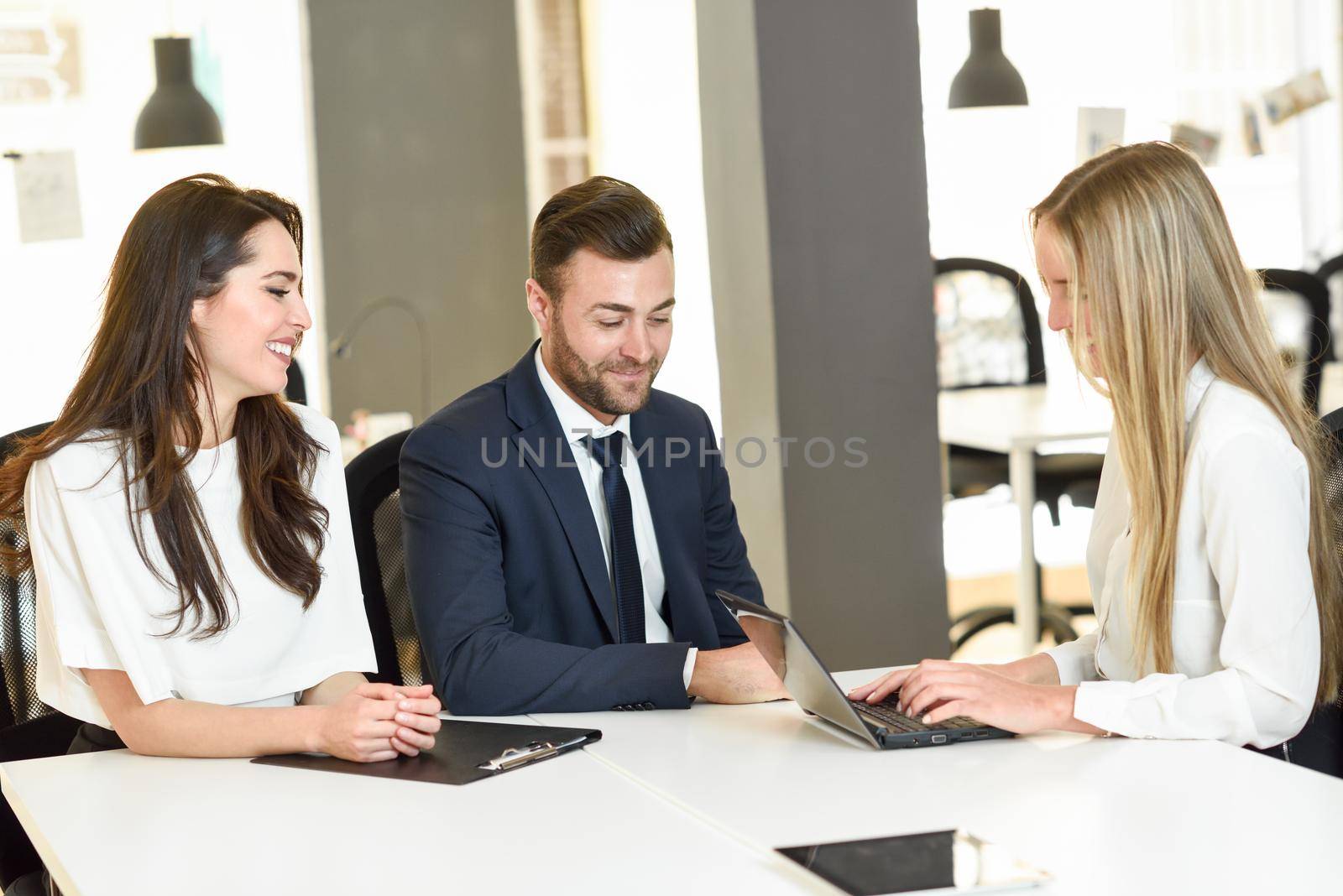 Blonde woman insurance agent or investment adviser explaining with laptop computer to a smiling young couple.