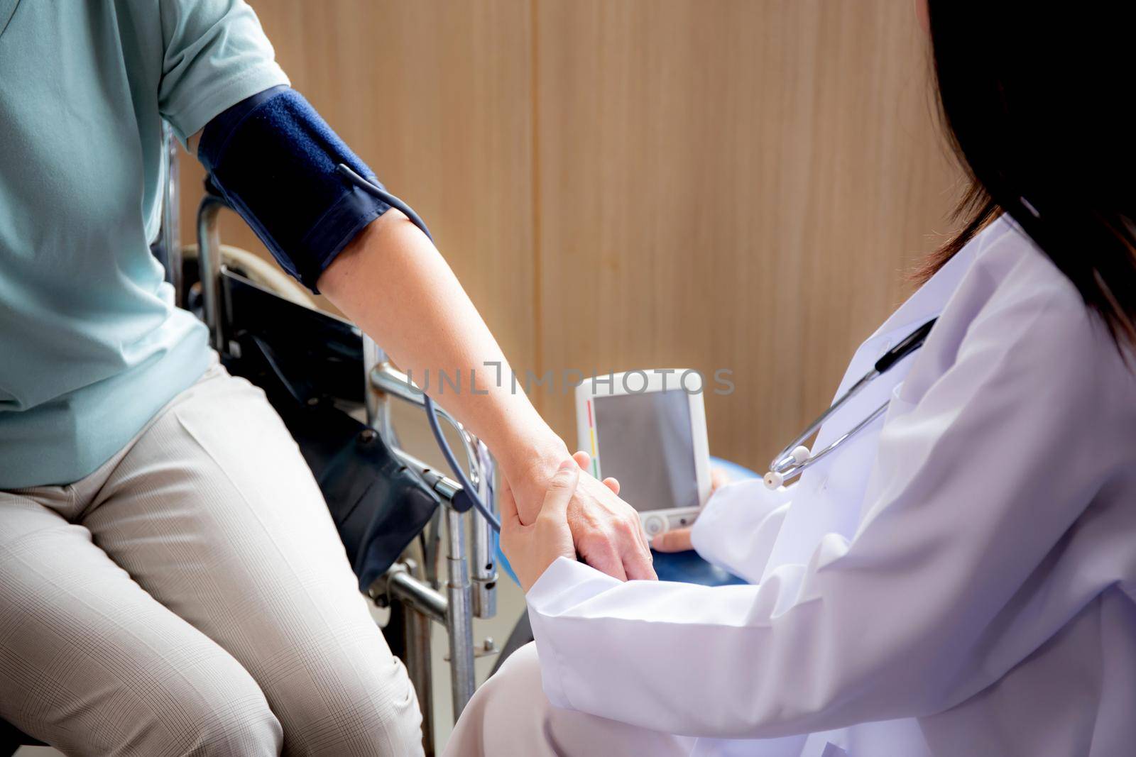 Doctor woman in uniform measuring blood pressure with patient elderly for checkup pulse health and examination at the hospital, physician and healthcare, diversity of ethnicity, medical concept.