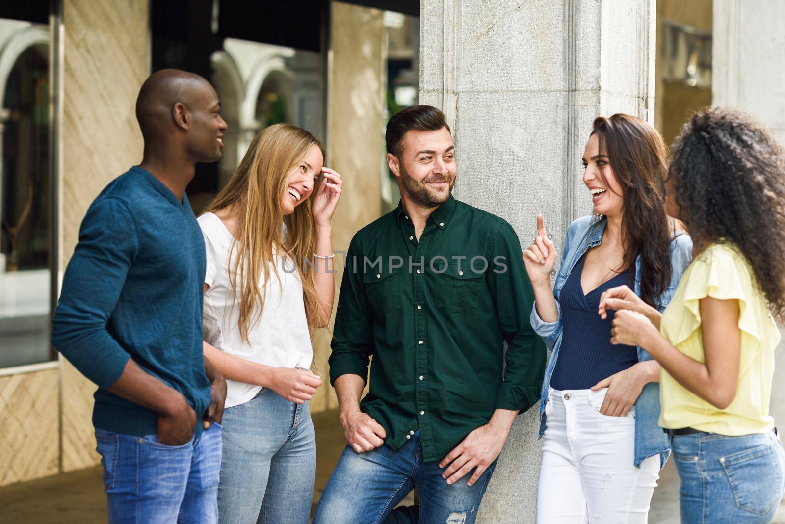 Multi-ethnic group of young people having fun together outdoors in urban background. group of beautiful women and men laughing together