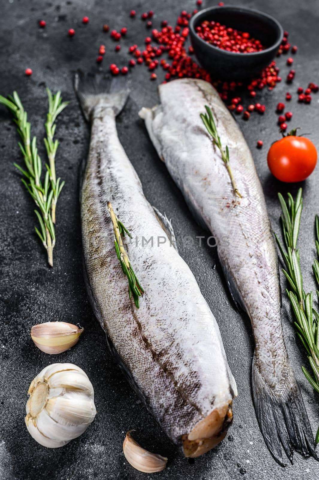 Fresh Pollock fish. Raw seafood. Black background. Top view.