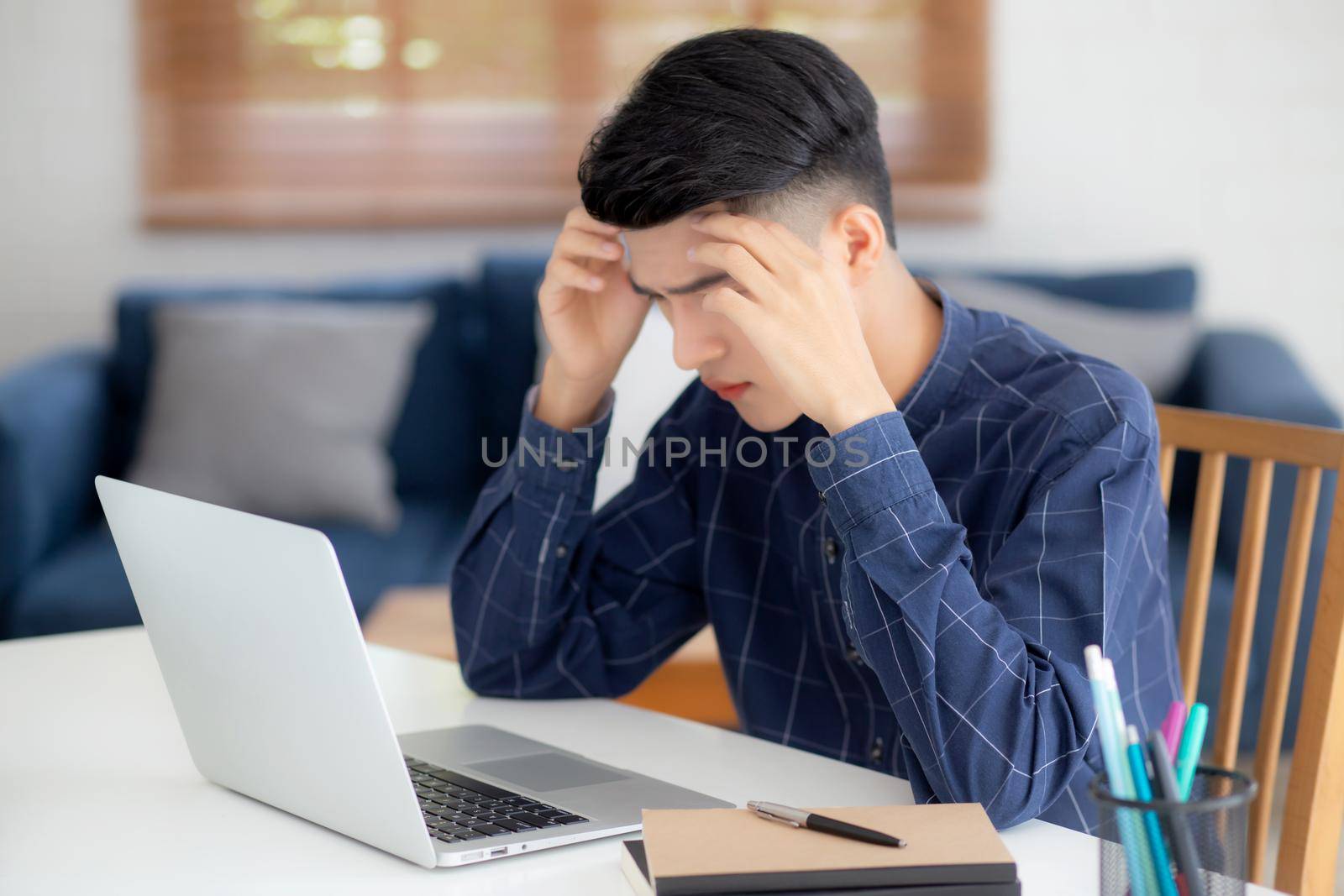 Young asian business man headache during working on laptop computer with deadline on desk at home, businessman with failure exhausted and tired, stress and worried, frustrated and unsuccessful.