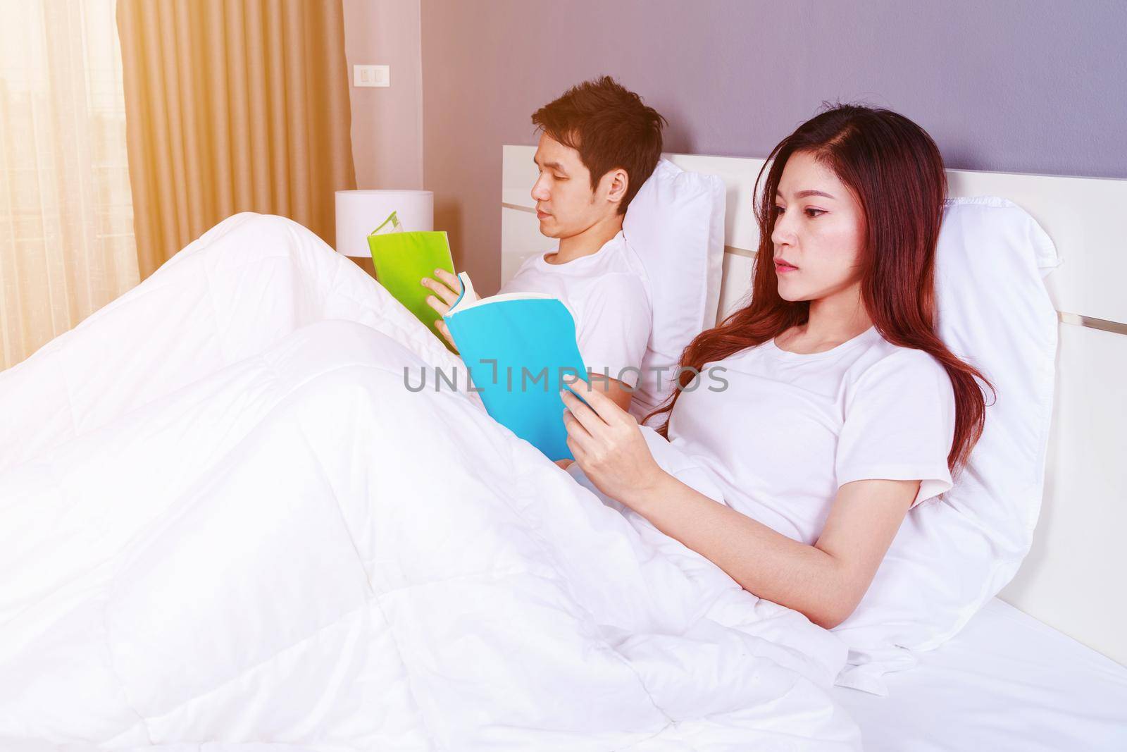 couple reading a book on bed in the bedroom by geargodz