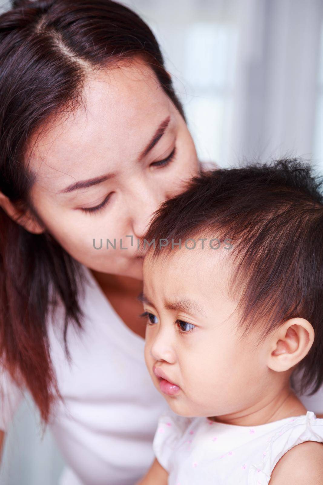 mother kissing head of baby at home