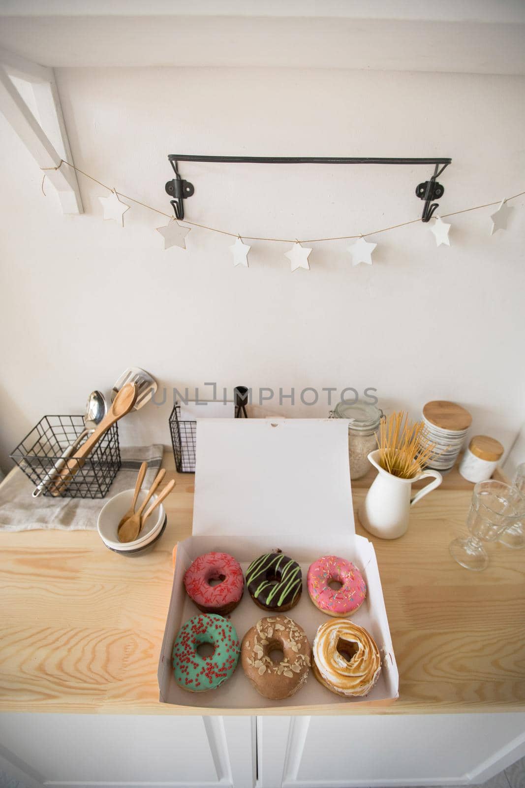 From above shot of open box with delicious fresh donuts lying on wooden tabletop in kitchen