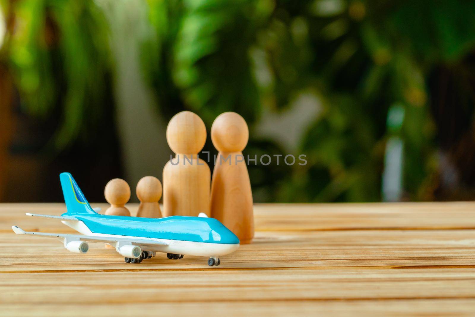 Family travel and vacation concept. Wooden figures of family and toy plane by Fabrikasimf