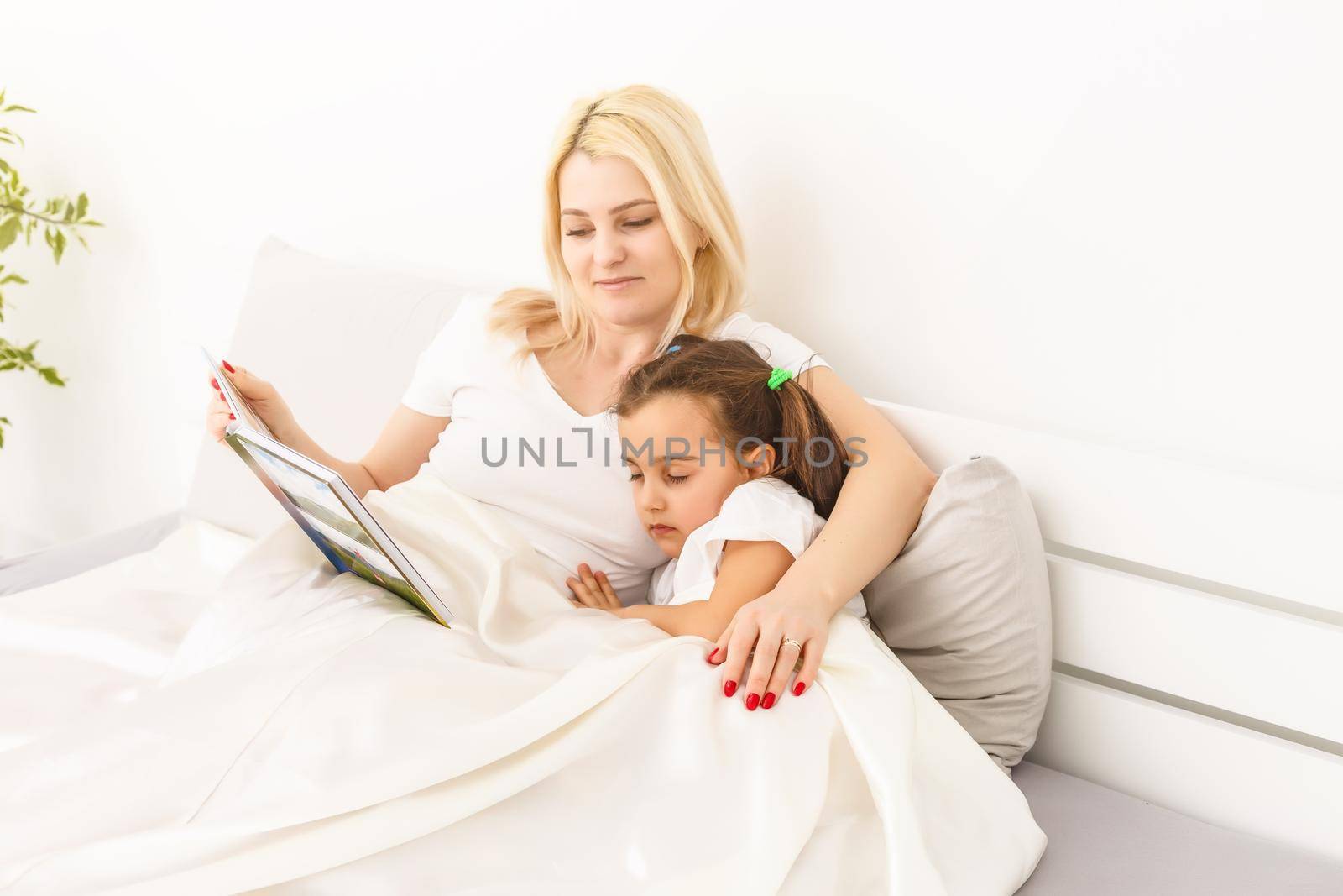 Woman holding with photo book and sitting on bed by Andelov13