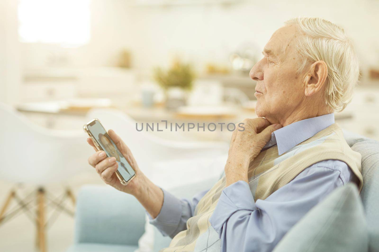 Pensioner looking at smartphone and chatting online with a doctor by friendsstock