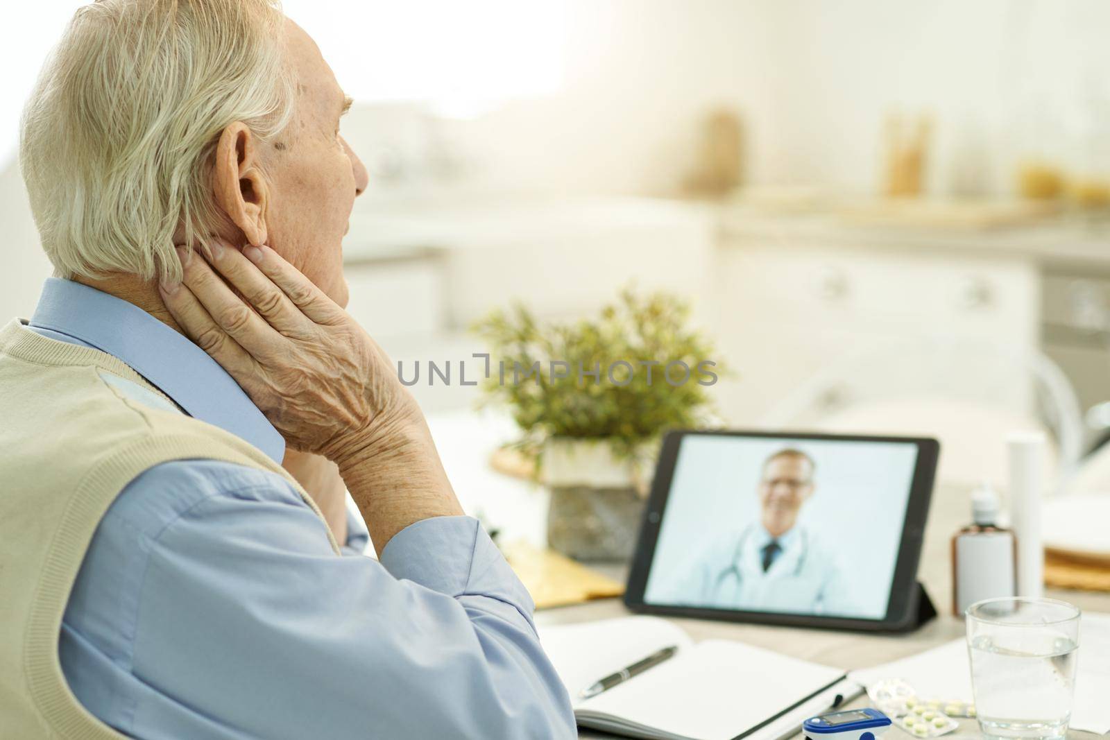 Copy space photo of aged man looking at tablet screen while having a video-calling with medical specialist
