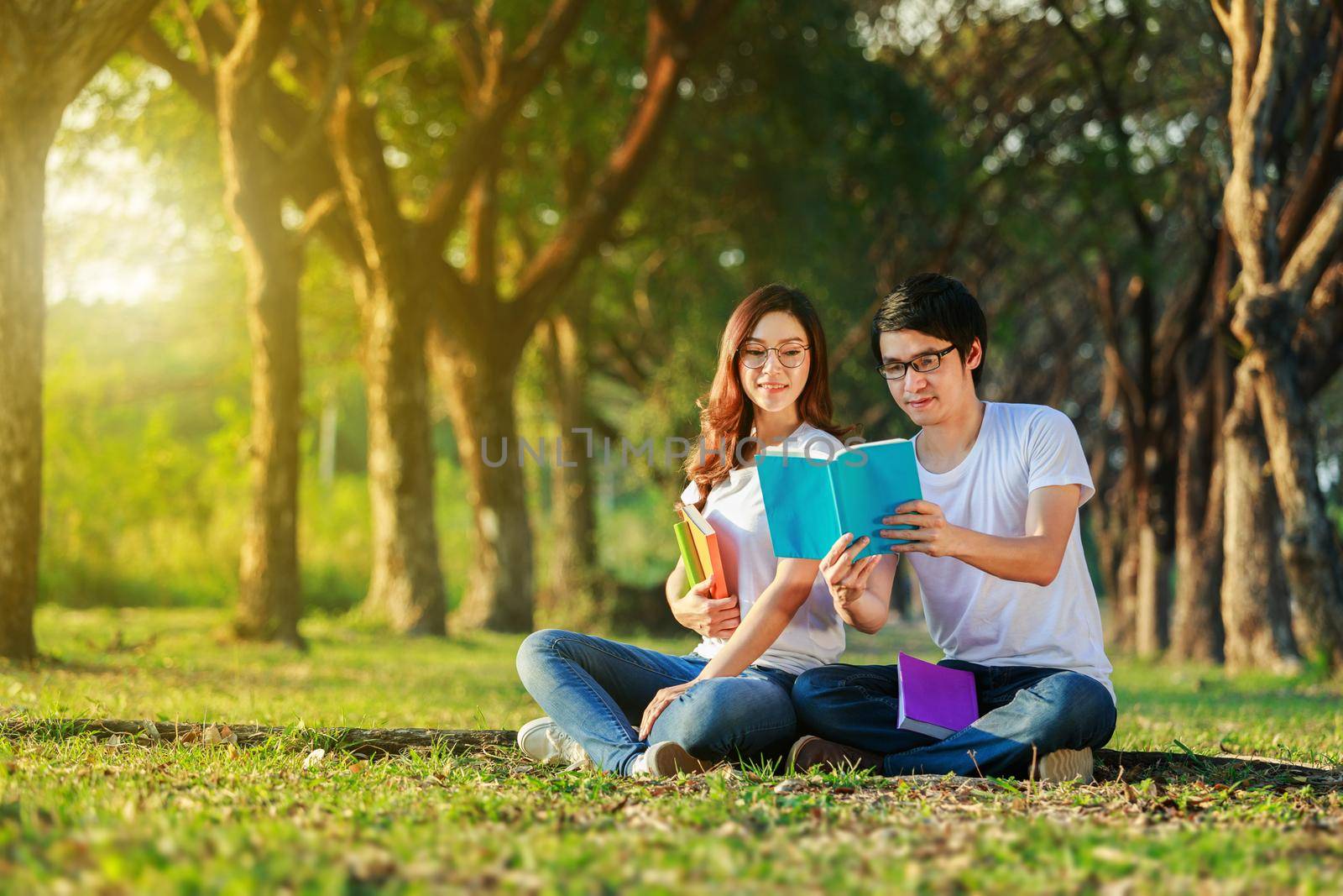 man and woman sitting and reading a book in the park by geargodz