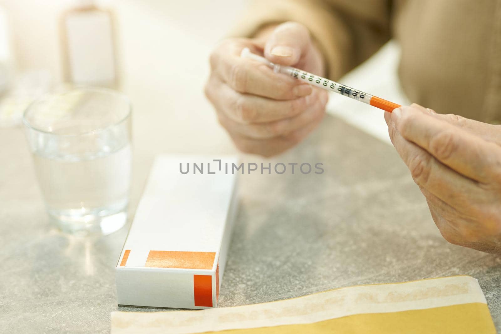 Cropped photo of senior man hands holding a thin syringe near a blank box of medication