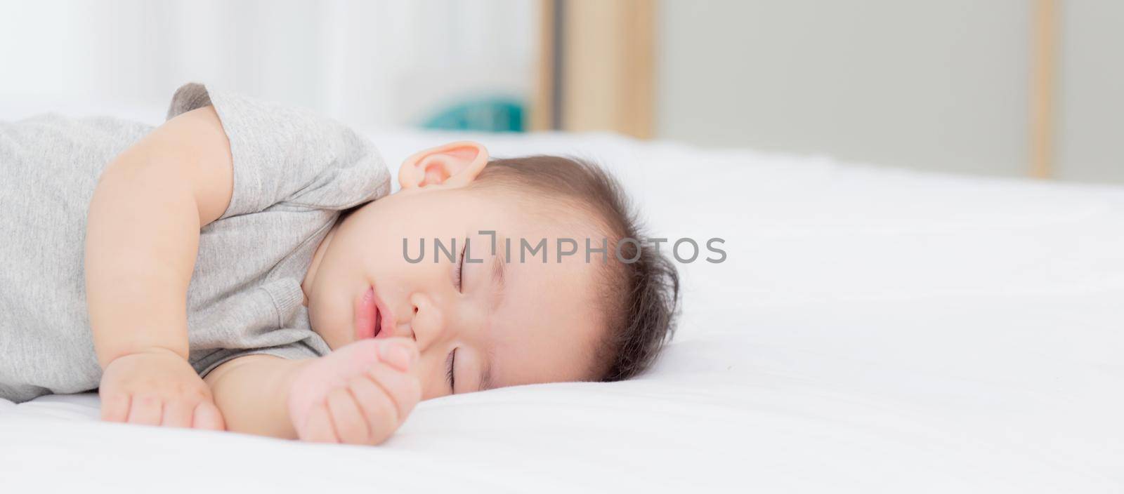 Portrait of asian little baby girl sleeping on bed in the bedroom at home, newborn napping with cozy and relax, infant innocence in bedtime, happy toddler cute, growth of child and emotion, indoors. by nnudoo